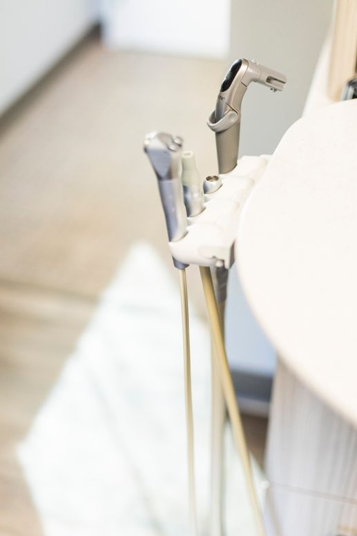 Close-up of modern dental tools attached to a treatment chair in a clean clinical setting