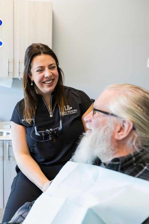 Dr Kacey at Lake Bowen Dental Studio smiling and speaking with a patient while seated in a dental chair