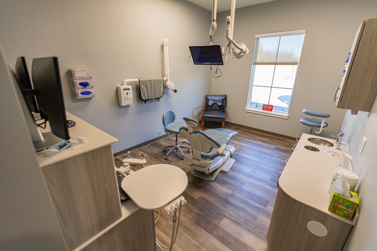 Modern dental exam room with patient chair, equipment, and natural light from window