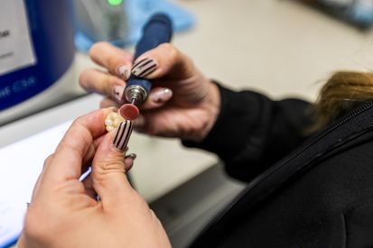A Lake Bowen Dental Studio team member carefully polishing a custom dental crown to ensure a precise natural fit
